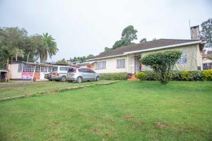 a house with two cars parked in a yard at The Nest Guest House in Kericho