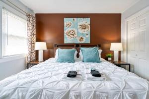 1 dormitorio con 1 cama blanca grande con almohadas azules en 2BR Duplex King Beds in the city- Great for small groups close to all Uptown Charlotte attractions, en Charlotte