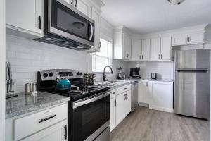 cocina con armarios blancos y fogones negros en 2BR Duplex King Beds in the city- Great for small groups close to all Uptown Charlotte attractions, en Charlotte