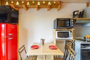 ジェラールメにあるAppart terrasse Vue Lacの小さなキッチン(木製テーブル、赤い冷蔵庫付)