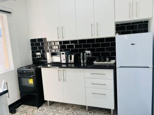 a kitchen with white cabinets and a black and white appliances at Safi Neat & Cozy Suite in East London