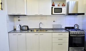a kitchen with white cabinets and a sink and a microwave at Córdoba Rent Apart in Córdoba
