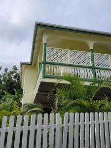 a white fence in front of a house with a balcony at Juju's Cottage with magnificent views in Laborie