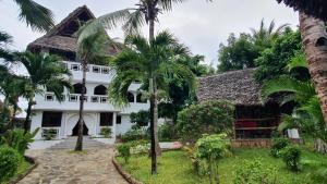 a white house with palm trees in front of it at Waridi House in Watamu