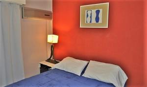 1 dormitorio con una pared roja, 1 cama y 1 lámpara en Córdoba Rent Apart en Córdoba