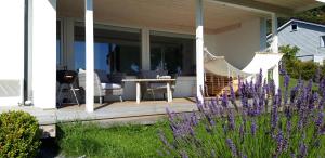 a porch with a hammock on a house with purple flowers at Relaxing place on Godøya in Godøy