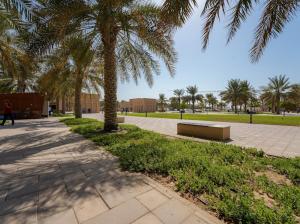 a park with palm trees and a bench on a sidewalk at Heritage Home Guest House in Dubai