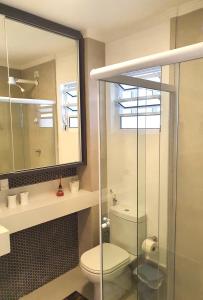 a bathroom with a toilet and a glass shower at Verdadeiro pé na areia TOP in Santos