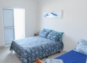a bedroom with a bed with a blue blanket at Verdadeiro pé na areia TOP in Santos