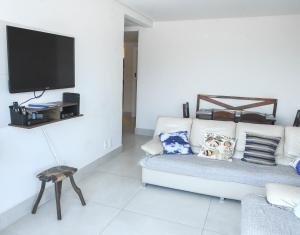 uma sala de estar com um sofá branco e uma televisão em Verdadeiro pé na areia TOP em Santos