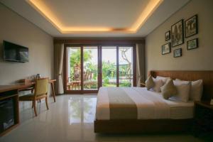- une chambre avec un lit, un bureau et une fenêtre dans l'établissement Queen at Gunung Sari, à Ubud