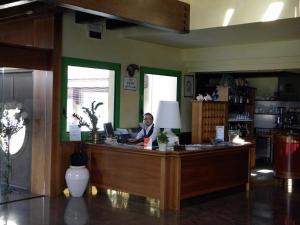 a man sitting at a reception desk in a room at Hotel Corone in Caerano di San Marco