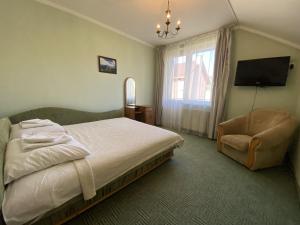una camera con letto, sedia e televisore di Edelweiss a Polyana