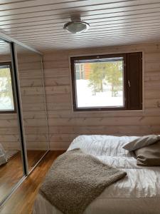 a bedroom with wooden walls and a bed with a window at VillaRiutta Ruka in Kuusamo