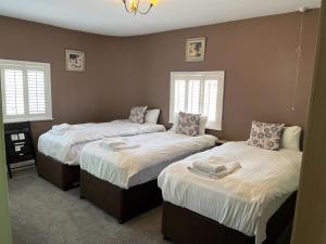 a bedroom with two beds and two windows at The Crown Hotel in Southwell