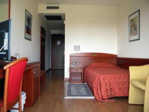 a bedroom with a bed with a red bedspread at Hotel Corone in Caerano di San Marco