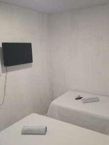 a white room with two beds and a flat screen tv at Pousada Lençóis do Delta in Tutóia