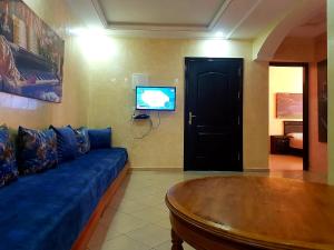 a living room with a blue couch and a tv at Dar Sara in Asilah