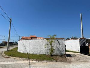 a white wall with a palm tree next to a street at Casa para aluguel de temporada em Caraguatatuba, ao lado de São Sebastião in Caraguatatuba +5 photos