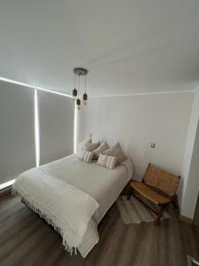 a white bedroom with a bed and a chair at Terrazas de Cochoa in Viña del Mar