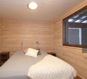 Cama en habitación de madera con ventana en VillaRiutta Ruka en Kuusamo