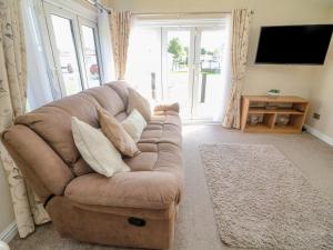 ein Wohnzimmer mit einem braunen Sofa und einem TV in der Unterkunft Number 15 in Carnforth