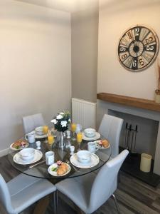 a table with plates of food and a clock on the wall at 2 Bedroom Luton Townhouse in Luton