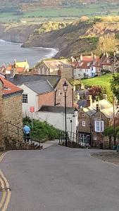 a small town with houses and the ocean in the background at Darnholm Cottage in Robin Hood's Bay
