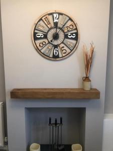 a clock on a wall above a fireplace at 2 Bedroom Luton Townhouse in Luton