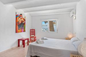 a white bedroom with a bed and a red chair at Villa Reva - PlusHolidays in Calpe +33 photos
