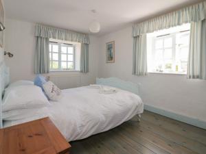 a bedroom with a white bed and two windows at Owls Roost in Saint Goran
