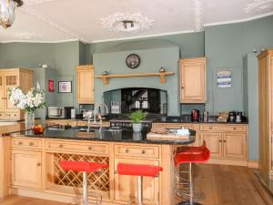 una cucina con armadi in legno e sgabelli rossi da bar di Ty Biwmares a Beaumaris