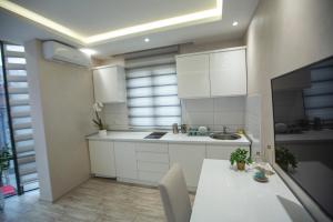 a kitchen with white cabinets and a sink and a table at Apartmani Rekic-Dubai in Novi Pazar