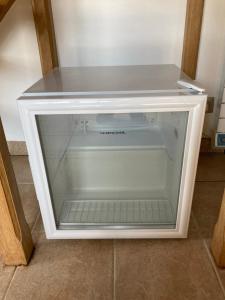 an empty refrigerator with a glass door on the floor at Charmante maisonnette indépendante in Broye