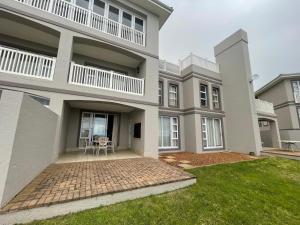 a large apartment building with a patio and grass at DunPuttin - Pinnacle Point Golf Estate in Mossel Bay