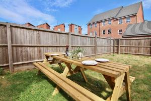 a wooden picnic table in a backyard with a fence at Serene 7Bed Escape - Steps from Coventry City Center, Holiday Bliss! in Coventry