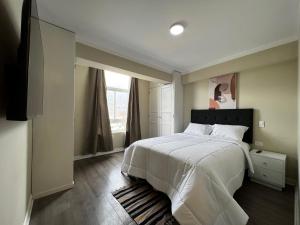 Un dormitorio con una gran cama blanca y una ventana en Departamentos Caraz, en Caraz