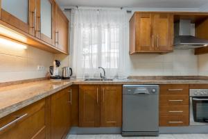 cocina con armarios de madera, fregadero y lavavajillas en Los Cristianos Duplex, en Arona