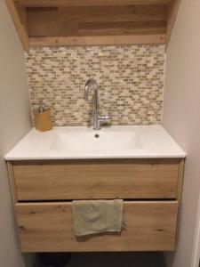 a white sink in a bathroom with a tile wall at Les pieds dans le sable in Roscoff +34 photos