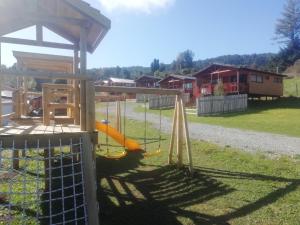 un parque infantil con un tobogán en el césped en Adilauquén Cabañas y Tinajas Calientes, en Puerto Varas