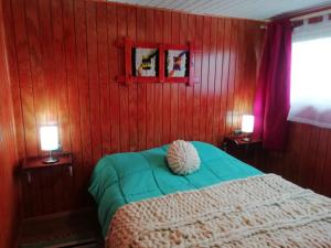 a bedroom with a bed with red walls and two lamps at Adilauquen Cabañas y Tinajas Calientes in Puerto Varas