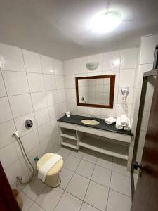 a bathroom with a sink and a toilet and a mirror at JL Temporadas - Quarto Portobello Park Hotel in Porto Seguro