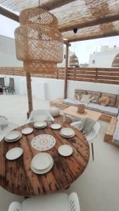 una mesa de madera con platos y sillas blancos en NOMAD SURF HOUSE, en Corralejo