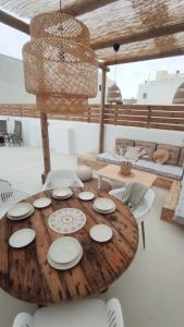 a wooden table with white plates and chairs at NOMAD SURF HOUSE in Corralejo