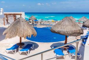 een strand met stoelen en parasols en de oceaan bij Villas Marlin by Andiani Travel in Cancun
