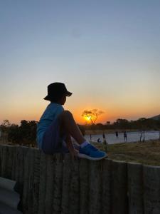 una persona seduta su una recinzione che guarda il tramonto di Estância Morro Do Frota a Pirenópolis