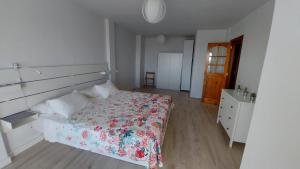 een witte slaapkamer met een bed met een bloemenbed bij Acogedor y Luminoso piso con balcón in Arona