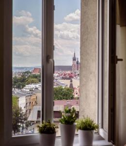 Urban Nest Apartments Łobzowska 57 في كراكوف: نافذة تحتوي على اثنين من النباتات الفخارية على حافة النافذة