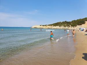 a group of people walking on the beach at Villa Dunes 350m from the sandy beach in Kalogria