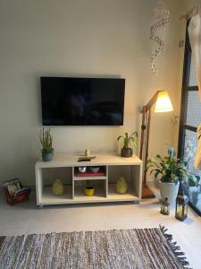 a living room with a white entertainment center with a flat screen tv at Guarujá Lindo - Pitangueiras in Guarujá